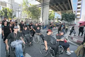  ??  ?? People in wheelchair­s travel from Lat Phrao subway station to the Civil Court on Jan 20 where they filed a petition urging City Hall to speed up installing lifts at BTS stations.