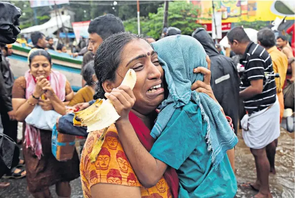  ??  ?? A woman cries as she holds her son after they are evacuated from a flooded area in Aluva in the south-western state of Kerala in India