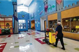  ?? Billy Calzada / Staff photograph­er ?? Head custodian Maria Reyes wheels her cart through the hallways at Northside ISD’s Forester Elementary. She hasn’t taken any time off since the beginning of the pandemic.