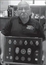  ??  ?? Dennis Ledbetter displays the badges that represent his career. His favorite is the smallest badge on the left. He received it for being a crossing guard when he was about 8 years old.