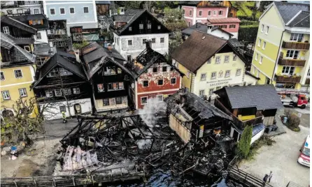  ??  ?? Brandruine­n in Hallstatt: Das Blechdach des kleinen Hauses links neben dem roten Haus hielt Flammen ab.