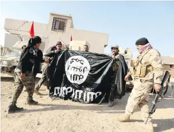  ?? HADI MIZBAN, THE ASSOCIATED PRESS ?? Iraqi soldiers celebrate as they hold a flag of the Islamic State group they captured during an operation to regain control of a village outside Mosul, Iraq, Tuesday.