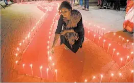  ?? ARINDAM DEY/GETTY-AFP ?? A volunteer lights candles placed in the shape of a red ribbon during an awareness rally Thursday on the eve of World AIDS Day in Agartala, a city in east India.