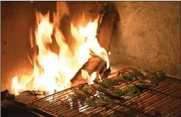  ??  ?? Mussels are roasted on an open fire during an opening party at The Slanted Door restaurant in San Ramon.