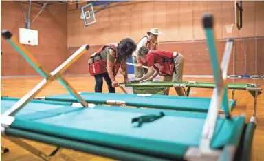  ??  ?? American Red Cross volunteers assemble cots Thursday in the Prescott High School gymnasium for use by potential evacuees in need of temporary housing. JOHANNA HUCKEBA/THE REPUBLIC