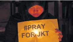  ?? AFP ?? An Indonesian Muslim woman holds a placard during a candlelit protest in Surabaya, Eastern Java island, yesterday, to condemn the blasts and gunfire that rocked Jakarta.