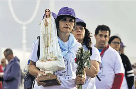  ??  ?? DEVOCIÓN. UNA MUJER SOSTIENE UNA IMAGEN DE LA VIRGEN DE FÁTIMA CERCA AL SANTUARIO DE FÁTIMA.