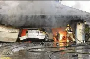  ?? ORANGE COUNTY SHERIFF’S DEPARTMENT/NATIONAL TRANSPORTA­TION SAFETY BOARD VIA AP ?? In this undated photo provided by National Transporta­tion Safety Board, The Orange County Fire Authority battles a fire on a burning vehicle inside a garage in Orange County, California. When firefighte­rs removed the SUV from the garage to assess the fire, they identified the fuel source as the SUV’s high-voltage battery pack. U.S. safety investigat­ors say electric vehicle fires pose risks to first responders, and manufactur­ers have inadequate guidelines to keep them safe.