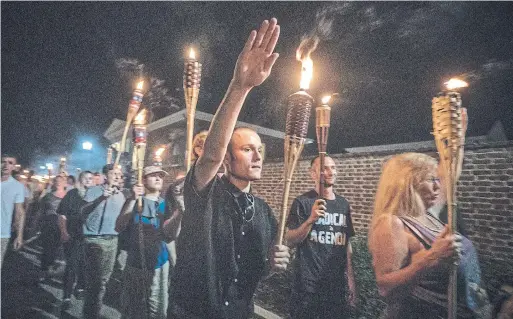  ?? EVELYN HOCKSTEIN THE WASHINGTON POST FILE PHOTO ?? Several hundred white nationalis­ts and white supremacis­ts carrying torches march through Charlottes­ville in August 2017.