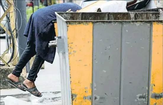  ?? ALI HASHISHO / REUTERS ?? Un hombre busca entre la basura en la ciudad libanesa de Sidón, con todo el país confinado