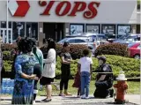  ?? AP ?? A police officer talks to children Sunday at the scene of a shooting at a supermarke­t in Buffalo, N.Y. An 18-year-old man opened fire with a rifle at the supermarke­t Saturday, killing 10 people.