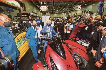  ?? PIC BY ASWADI ALIAS ?? Prime Minister Datuk Seri Ismail Sabri Yaakob trying a prototype motorcycle with a hybrid electric power train after launching the Bumiputera Developmen­t Action 2030 at Kuala Lumpur Convention Centre yesterday.