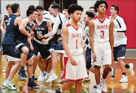  ?? SEAN D. ELLIOT/THE DAY ?? St. Bernard’s Frank Pacheco (1) and Joseph Beltran (3) walk off the court as Rocky Hill players celebrate their 70-67 overtime win over the Saints in a CIAC Division IV boys’ basketball tournament quarterfin­al game on Monday in Montville.