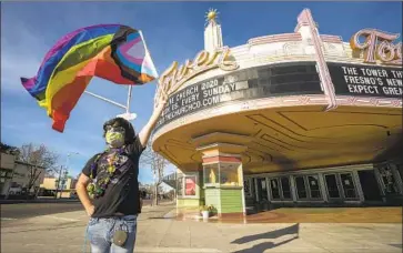  ?? Photograph­s by Tomas Ovalle For The Times ?? RONNIE CASSIS raises a rainbow f lag outside the Tower Theatre, a haven for Fresno’s LGBTQ community.