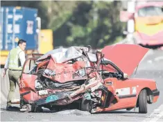  ??  ?? A policeman walks past the crushed taxi after a coach (back) rammed into it. — AFP photo