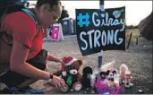  ?? Kent Nishimura Los Angeles Times ?? LAURA MILLER places a stuffed bear at a memorial to those killed in the Gilroy shooting.