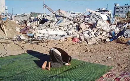  ?? PIC BY AHMAD A TALIB ?? A Palestinia­n man praying among the rubble of homes and buildings destroyed by Israeli fighter aircraft.