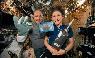  ?? AP ?? In this photo made available by US astronaut Christina Koch, she and Italian astronaut Luca Parmitano pose for a photo with a cookie baked on the Internatio­nal Space Station.