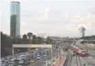  ?? (Corinna Kern/Reuters) ?? NEW TRANSPORTA­TION TECHNOLOGI­ES may lead to Israel’s roads becoming even more crowded. See here: cars drive on a highway as a train enters a railroad station in Tel Aviv.