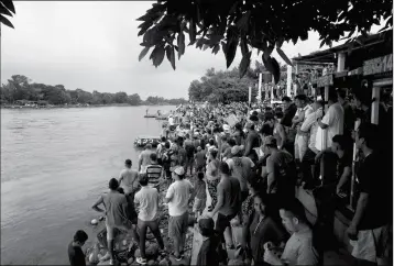  ?? ASSOCIATED PRESS ?? HUNDREDS OF HONDURAN MIGRANTS STAND AT THE SHORE of the Suchiate river on the border between Guatemala and Mexico, in Tecun Uman, Guatemala, on Thursday. Mexico’s foreign ministry says government officials at its southern border with Guatemala have started assisting the early arrivals from a caravan of some 3,000 Honduran migrants that has drawn sharp criticism from U.S. President Donald Trump.