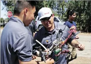  ??  ?? Khai Chang (left), and Freddy Lopez look over their drone during a University of California Cooperativ­e Extension field day at a Bowles Farming Co. cotton field in Los Banos. The group from California State University, Fresno, is working with UCCE farm...