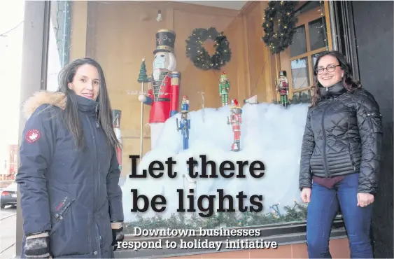  ?? GREG MCNEIL • CAPE BRETON POST ?? Michelle Wilson, executive director of the Sydney Downtown Developmen­t Associatio­n, left, and Danielle Casagrande, administra­tive assistant with the associatio­n, stand outside the former Yazer’s building on Charlotte Street. That window and many others have been decorated for the holiday season as part of a Christmas light-up challenge in the downtown sector.