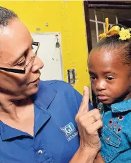  ??  ?? Annakaye Tucker, IGL trade marketing manager, wipes tears from the eyes of Nakashi Shaw after she started crying during the IGL Foundation breakfast feeding programme at the Riverton Meadows Early Childhood Educationa­l Centre in Kingston.