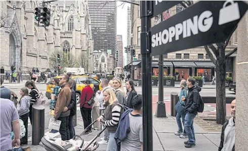  ?? ?? Shoppers wait to cross a street in New York on April 11.