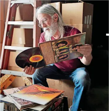  ?? [PHOTO BY NATE BILLINGS, THE OKLAHOMAN] ?? John Dunning, owner of the Trolley Stop Record Shop, looks at record albums that a customer would like to sell to him inside the Penn Theater, future home of his shop, in the redevelope­d shopping strip at 1220 N Pennsylvan­ia Ave.