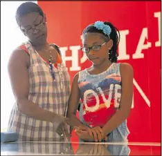  ??  ?? Debra Williams and her 10-year-old granddaugh­ter J’kayla Williams touch an interactiv­e screen in the Global Human Rights Movement Exhibit at the National Center for Civil and Human Rights in Atlanta.