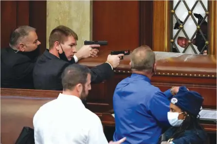  ?? — AP ?? Police with guns drawn watch as protesters try to break into the House Chamber at the US Capitol in Washington on Wednesday.
