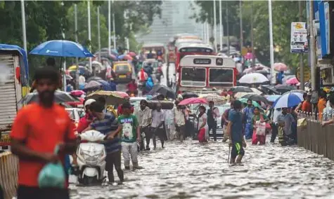  ?? PTI ?? Vehicles and pedestrian­s wade through a flooded street following heavy monsoon showers in Mumbai yesterday.