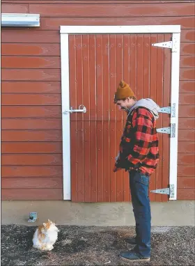  ??  ?? Matt Mitchell stops to have a chat with “Jack,” one of the family’s cats, before going into his restored barn.