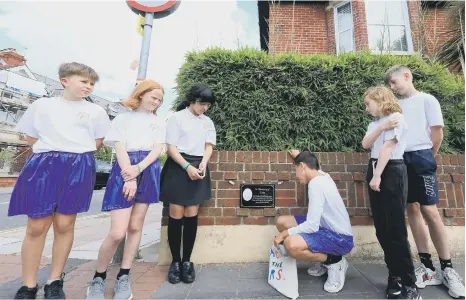  ?? ?? Wimborne Primary School pupils alongside the plaque in memory of their beloved lollipop man, Tom James – pictures: Chris Moorhouse