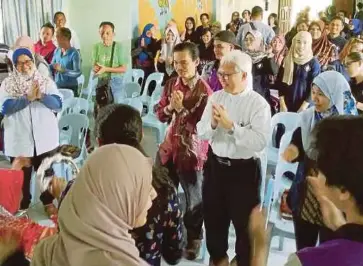  ??  ?? DR Ismail (dua dari kanan) bersama pelajar UNIMAS menghiburk­an pesakit.