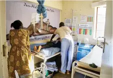  ?? ?? A mother watches as a health worker tends to her son recuperati­ng in the paediatric ward at Karanda Mission Hospital in Mount Darwin.