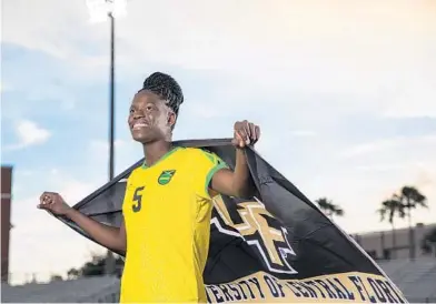  ?? COURTESY OF NICK LEYVA/UCF ATHLETICS ?? Orlando Pride rookie Konya Plummer poses in her Jamaican national team jersey with a University of Central Florida flag.