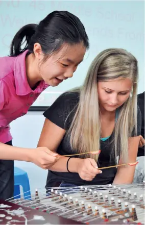  ??  ?? An American middle school student is learning to play yangqin from a Chinese student at Hefei No. 45 Middle School of Anhui Province.