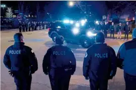  ?? JOHN J. KIM/CHICAGO TRIBUNE ?? Chicago police officers stand in formation as a procession for Chicago police officer Jeffrey T. Troglia reaches the Cook County medical examiner Friday. The 38-year-old died by apparent suicide earlier in the evening, according to police.