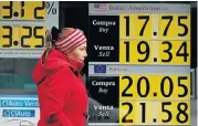  ?? Picture: REUTERS ?? RECORD DIVE: A woman walks past boards displaying the exchange rates of the Mexican peso against the dollar and the euro at a CI bank branch in Mexico City