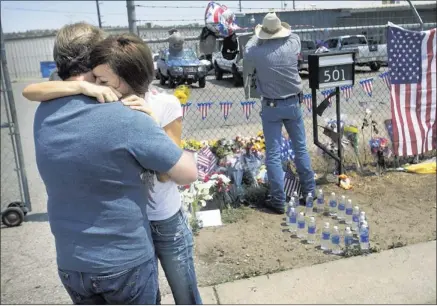  ?? DAVID WALLACE/ASSOCIATED PRESS ?? Juliann Ashcraft, the wife of Andrew Ashcraft, who was killed battling the Yarnell Hill Fire, hugs Andrew’s father, Tom Ashcraft, in front of Prescott Fire Station #7 on Monday. Ashcraft and 18 other firefighte­rs died in the fire that has ripped...