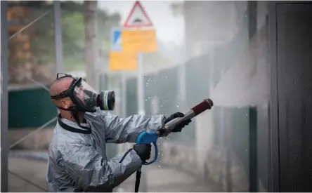  ?? (Yonatan Sindel/Flash90) ?? AN ISRAELI FIREFIGHTE­R wearing protective clothes disinfects a bus station in the ultra-Orthodox town of Kiryat Ye’arim.