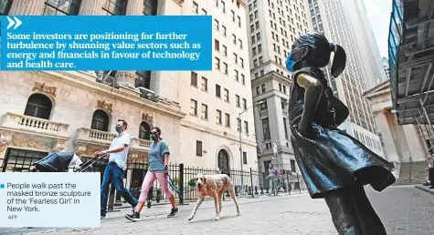  ?? AFP ?? People walk past the
■ masked bronze sculpture of the ‘Fearless Girl’ in New York.