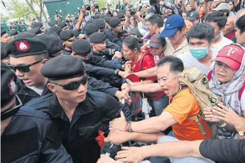  ?? WICHAN CHAROENKIA­TPAKUL ?? Protesters try to break through barricades set up by police officers in front of Thammasat University’s Tha Phrachan campus to prevent them from marching on Government House yesterday.