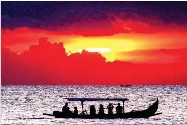  ?? SONNY TUMBELAKA/AFP ?? Foreign tourists on a traditiona­l boat enjoy the sunset at Kuta beach in Bali, Indonesia.