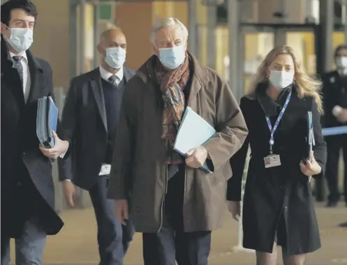  ??  ?? 0 EU chief Brexit negotiator Michel Barnier, center, wears a protective face mask as he leaves the EU headquarte­rs in Brussels