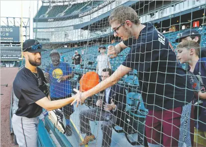  ?? PHOTOS BY CHARLES REX ARBOGAST/ASSOCIATED PRESS ?? Geoffrey Boston from Elgin, Ill., right, reaches for his hat through a seam in the newly extended protective netting along right field after Marlins relief pitcher Nick Anderson, left, autographe­d a cap before a Monday game against the White Sox in Chicago.