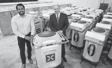  ?? Jerry Lara / Staff photograph­er ?? Xenex CEO Morris Miller, right, and engineer Deepak Jayaraj show germ-killing robots. Miller defines a robot as a machine programmed by a computer that carries out actions automatica­lly.