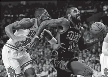  ?? WINSLOW TOWNSON/AP PHOTO ?? The Celtics’ Kyrie Irving elbows Chicago’s Kris Dunn on the chin as he drives to the basket during Saturday night’s game in Boston. The Celtics beat the Bulls 117-92, holding Dunn, the ex-New London star, to only two points.