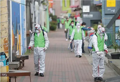 ??  ?? Health workers disinfect a street to curb the spread of coronaviru­s in Daegu, South Korea
